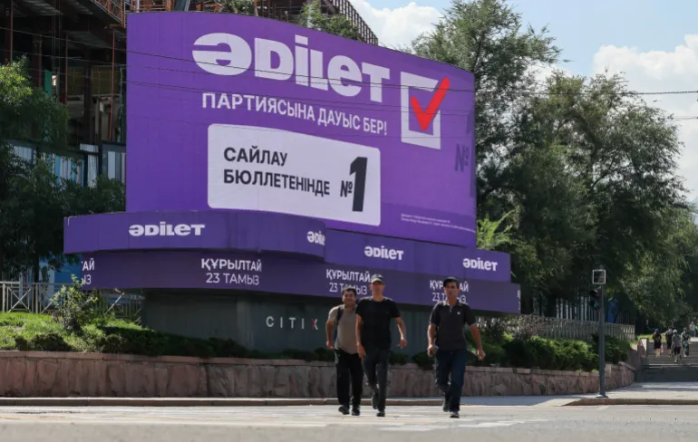 Pedestrians walk past an electronic screen promoting the Adilet (Justice) party before Kazakhstan’s upcoming parliamentary election in Almaty, Kazakhstan, August 17, 2026