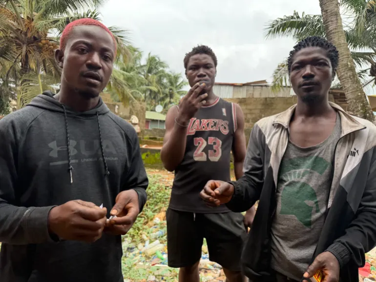 Abraham Jackson, 26, far right, sits with other kush users at a drug den in Monrovia. Users are known locally as zogos. [Lennart Dodoo/Al Jazeera]