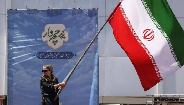 This image depicts a woman waving the Iranian flag at Valiasr Square in Tehran on June 15, 2026. — AFP