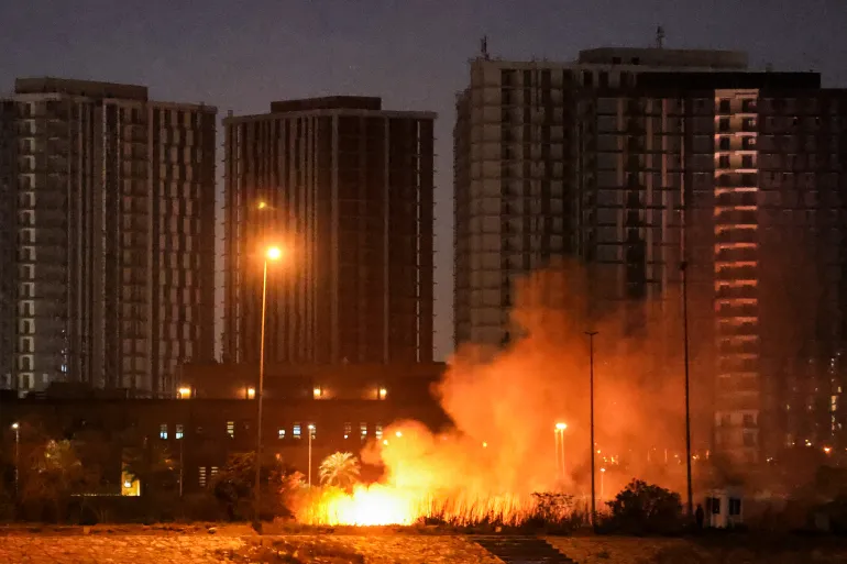 CORRECTION / A fire burns outside the grounds of the US Embassy headquarters in Baghdad's fortified "Green Zone" on March 17, 2026 following a drone and rocket attack according to security officials.