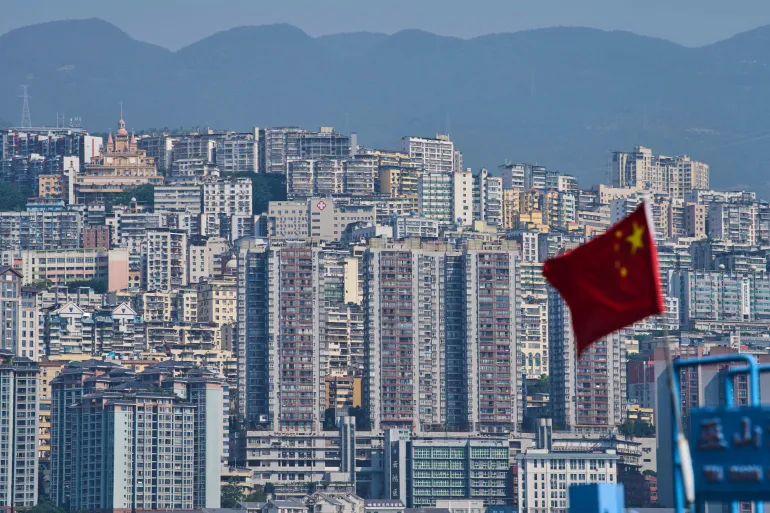 A Chinese national flag flutters against the high-rise residential buildings in Wushan county, in southwest China’s Chongqing Municipality, Wednesday, May 21, 2025. Chongqing is one of the major inland regions that the canal will connect to Southeast Asia