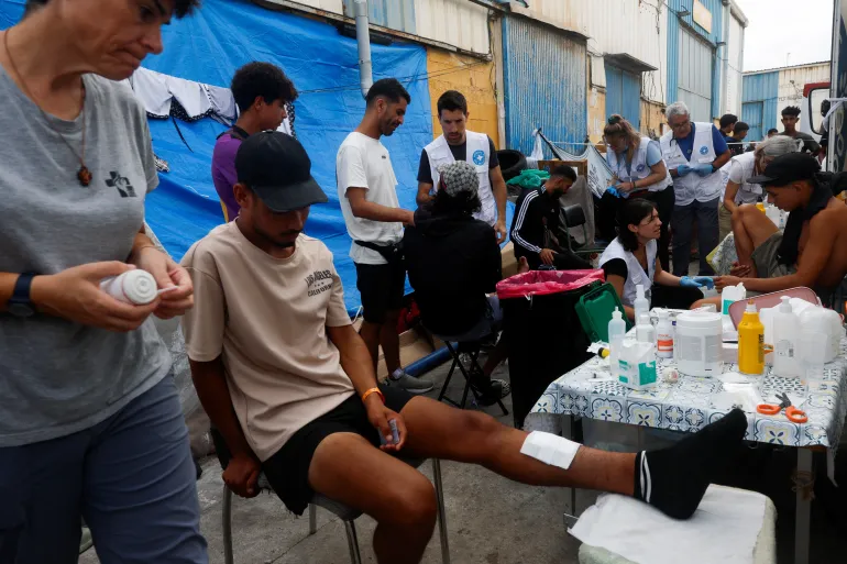 Members of a Spanish NGO Medicos del Mundo (Doctors of the World) help injured migrants at an industrial area, following the mass crossing of migrants from Morocco, in Ceuta, Spain, September 21, 2026. REUTERS/Jon Nazca