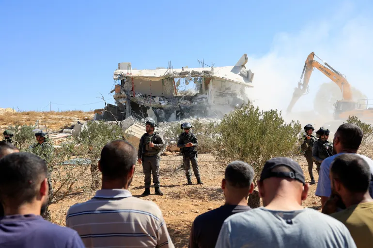Palestinian men watch as Israeli forces stand guard during the demolition of a Palestinian building near Hebron in the Israeli-occupied West Bank, an area that Netanyahu referred to as a ‘front’ Israel was successfully fighting