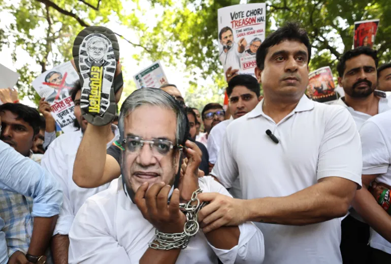 epa13262137 An Indian Youth Congress activist, wearing a mask depicting Chief Election Commissioner Gyanesh Kumar and handcuffed, takes part in a protest in New Delhi, India, 25 September 2026. Demonstrators gathered to demand Gyanesh Kumar's resignation over controversies surrounding the Election Commission's Special Intensive Revision (SIR) of electoral rolls and alleged voter irregularities during recent elections. EPA/RAJAT GUPTA