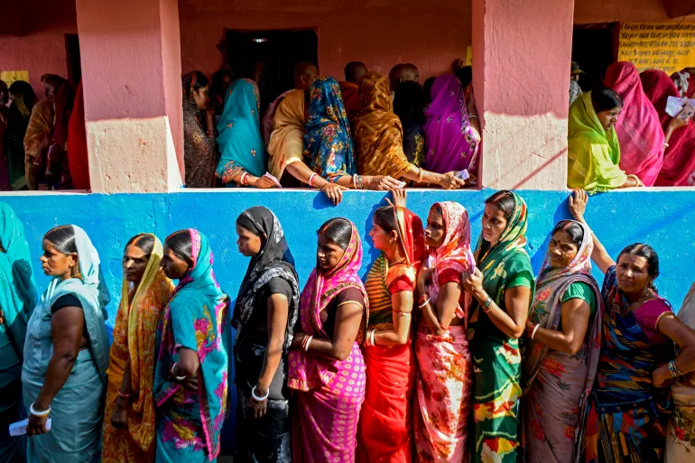 Women voters stand in queues to cast their ballots at a polling station during the first phase of voting for assembly elections on November 6, 2025, at the Raghopur constituency in the Vaishali district of the Indian state of Bihar