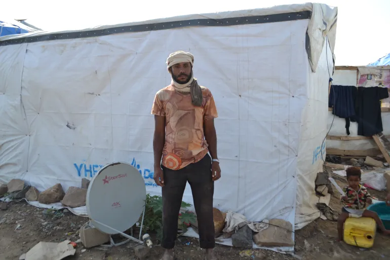Hasnaa’s father Jaber Ali stands beside his shelter before heading to work to wash cars