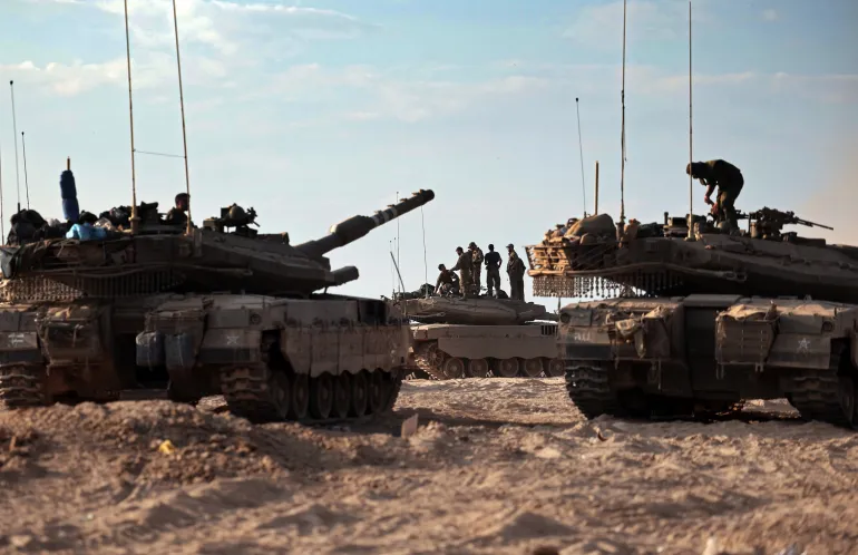 Israeli troops and tanks gather in a field near the kibbutz Beeri in southern Israel on October 14, 2023, close to the spot where 270 revellers were gunned down or burnt in their cars by Hamas gunmen at the Supernova music festival in the Negev desert on October 7. - Hamas launched a large-scale attack on Israel on October 7 which killed at least 1300 people, sparking a retaliatory bombing campaign that has killed more than 1900 in the Gaza Strip ahead of a potential Israeli ground invasion of the territory. (Photo by Thomas COEX / AFP)