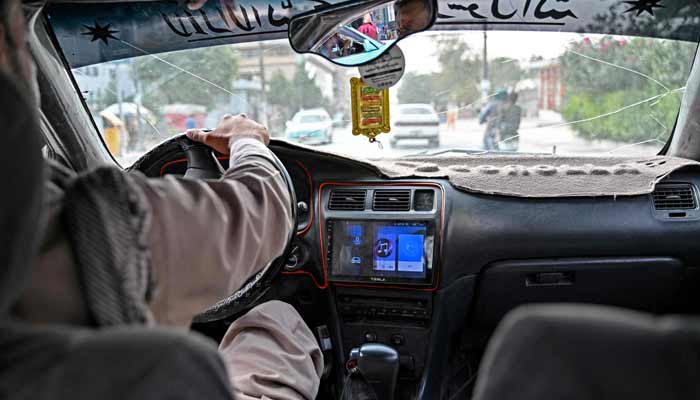 A music playback screen on the stereo as an Afghan taxi driver transports passengers in Kabul. — AFP
