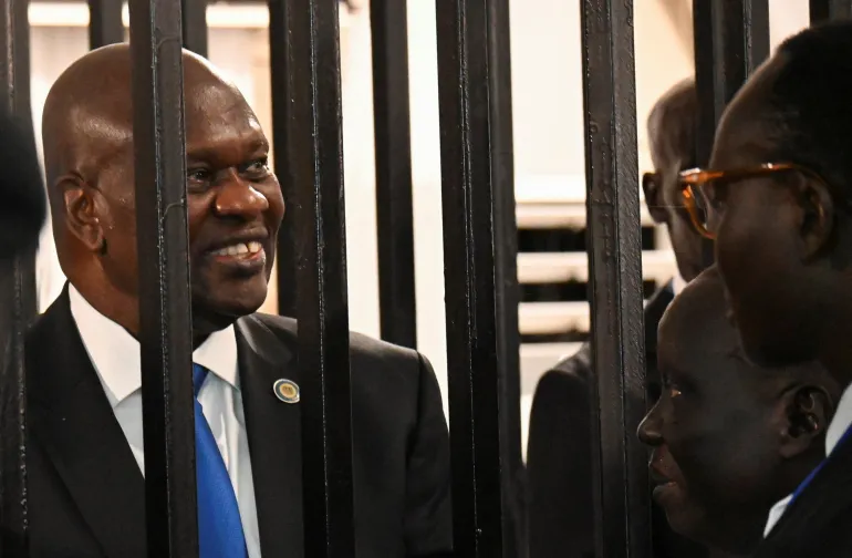 South Sudan’s suspended First Vice President Riek Machar stands inside a steel caged dock as he talks to his legal counsel before his trial on charges including treason and crimes against humanity, at the Freedom Hall in Juba, South Sudan, September 22, 2025. REUTERS/Stringer