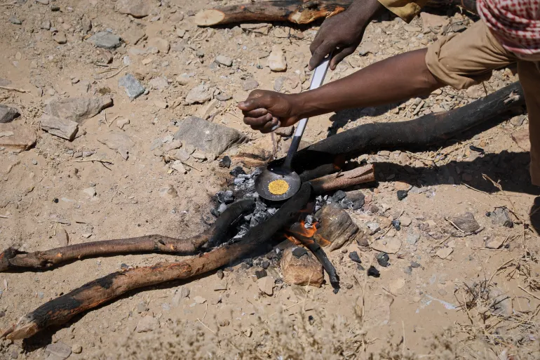Miners heat processed gold concentrate over an open fire at an artisanal mining site in Dalago Mahas, Sudan's Northern State, Friday, May 8, 2026.(AP Photo/Mohnd Blal)