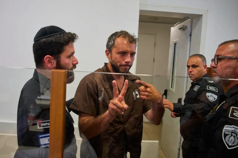 Brazilian activist Thiago Ávila, center, a member of the Global Sumud Flotilla, is escorted by prison service guards to a hearing at the District Court in Ashkelon, Israel, on Sunday, May 3, 2026. (AP Photo/Ohad Zwigenberg)