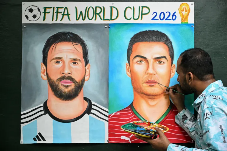 An artist adds final touches to a painting featuring football players Argentina's Lionel Messi and Portugal's Cristiano Ronaldo in Amritsar on June 11, 2026 on the eve of the 2026 FIFA World Cup tournament. (Photo by Narinder NANU / AFP)