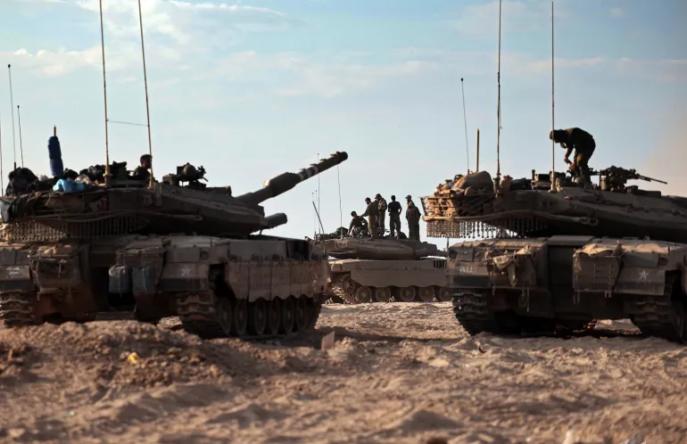 Israeli troops and tanks gather in a field near the kibbutz Beeri in southern Israel on October 14, 2023, close to the spot where 270 revellers were gunned down or burnt in their cars by Hamas gunmen at the Supernova music festival in the Negev desert on October 7. - Hamas launched a large-scale attack on Israel on October 7 which killed at least 1300 people, sparking a retaliatory bombing campaign that has killed more than 1900 in the Gaza Strip ahead of a potential Israeli ground invasion of the territory. (Photo by Thomas COEX / AFP)