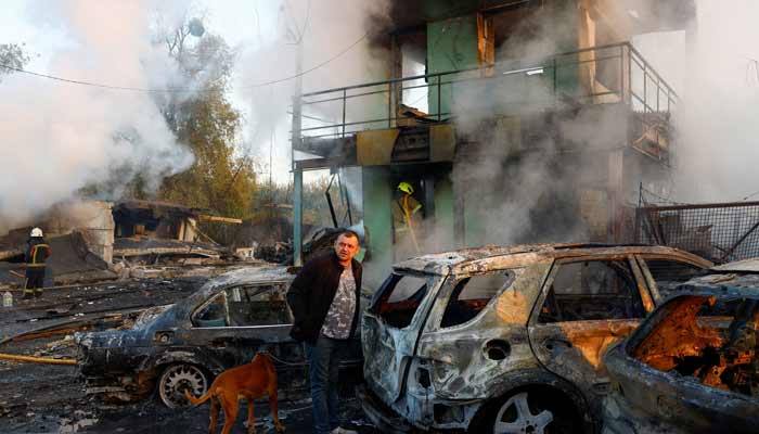 A resident with a dog looks on at the site of private car garages hit by a Russian missile strike, amid Russias attack on Ukraine, in Kyiv, Ukraine, October 7, 2026. — Reuters
